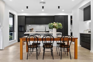 Een moderne keuken met donkere kastjes, een centraal eiland en een eethoek met vier stoelen.