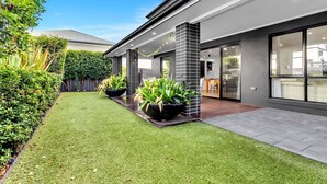 A modern house with a well-maintained lawn, large planters, and a visible kitchen area.