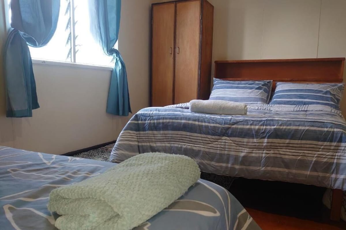 Een slaapkamer met twee bedden, een garderobe en een raam met gordijnen.