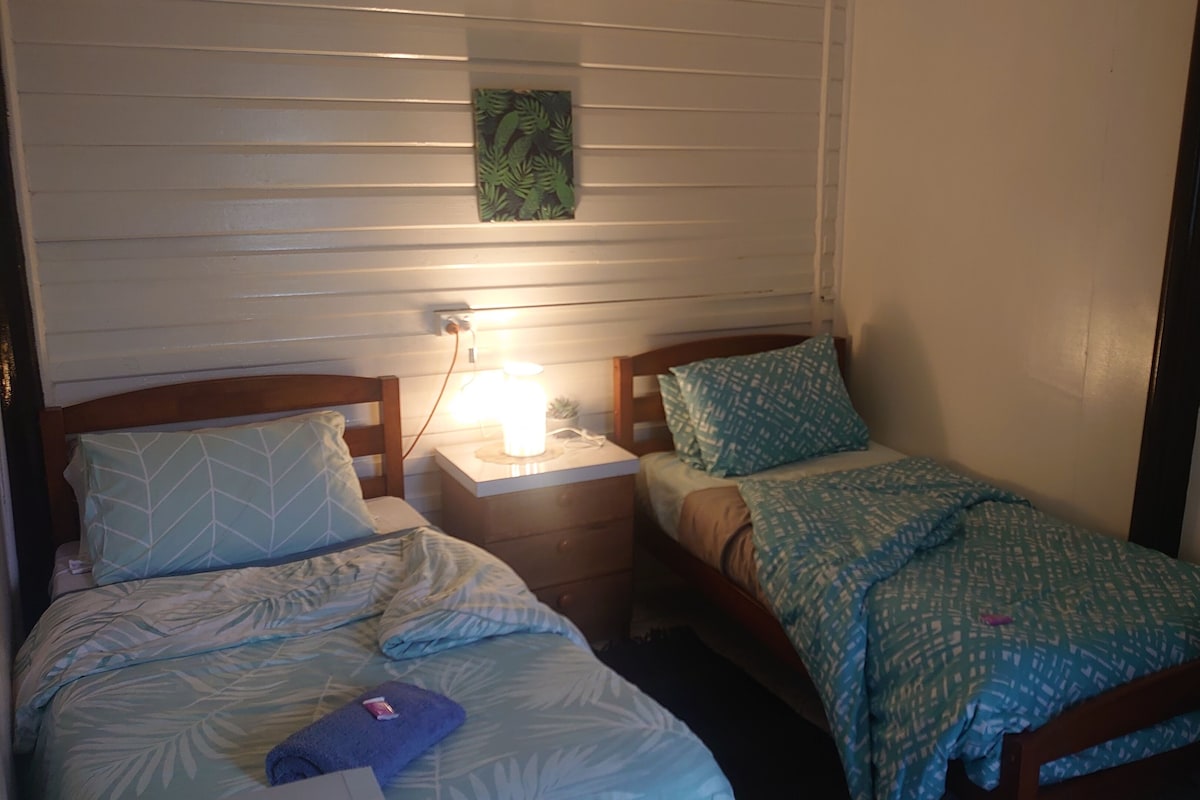 Een slaapkamer met twee bedden, een nachtkastje met een lamp en een kunstwerk aan de muur.