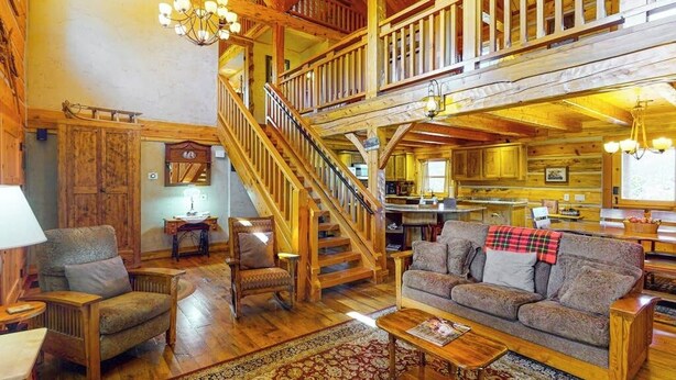 A spacious living area with a wooden staircase, a sofa set, and a dining area. - Ridgetop mountain-view home on 5 acres with Gas Grill, AC & fireplace (Pagosa Springs)