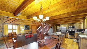 A log cabin interior with a dining area, kitchen, and staircase. - Ridgetop mountain-view home on 5 acres with Gas Grill, AC & fireplace (Pagosa Springs)