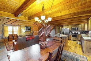 A log cabin interior with a dining area, kitchen, and staircase. - Ridgetop mountain-view home on 5 acres with Gas Grill, AC & fireplace (Pagosa Springs)