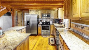 A kitchen with wooden cabinets, granite countertops, stainless steel appliances, and a wooden ceiling. - Ridgetop mountain-view home on 5 acres with Gas Grill, AC & fireplace (Pagosa Springs)