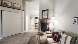 A living room with a fireplace, a sofa, a coffee table, and framed pictures on the wall. - Dog-friendly studio with mountain views - near lakes, golf, ski area (Pagosa Springs)
