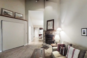A living room with a fireplace, a sofa, a coffee table, and framed pictures on the wall.