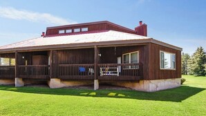 A wooden cabin with a covered porch, a chimney, and a well-maintained lawn. - Dog-friendly studio with mountain views - near lakes, golf, ski area (Pagosa Springs)