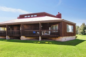 A wooden cabin with a covered porch, a chimney, and a well-maintained lawn.
