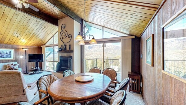 Un interior acogedor con techo de madera, una mesa redonda para comer, sillas de mimbre y una chimenea.