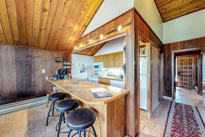 Eine Küche mit Holzbalkendecke, einer Bar mit Barhocker und einer Mikrowelle.