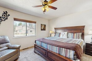 Ein Schlafzimmer mit Bett, Deckenventilator, Fenster, Stuhl und Lampe.