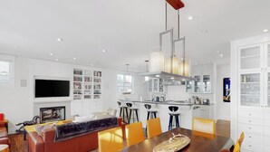 A modern living room with a sofa, dining table, and chairs, a kitchen area with bar stools, and a TV mounted on the wall. - Beautiful Telluride house close to gondolas with private hot tub & fireplace (Telluride)