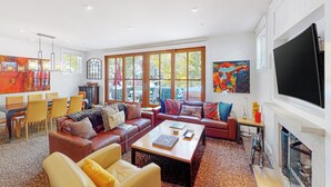 A spacious living room with a fireplace, a dining area, and large windows. - Beautiful Telluride house close to gondolas with private hot tub & fireplace (Telluride)