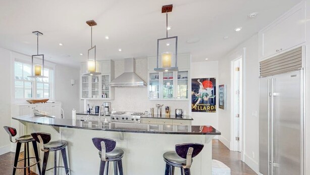 A modern kitchen with a central island, bar stools, pendant lights, and a stainless steel refrigerator. - Beautiful Telluride house close to gondolas with private hot tub & fireplace (Telluride)