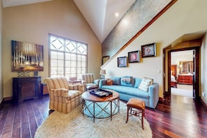A living room with a blue sofa, striped armchairs, a round coffee table, and a fireplace. - Luxury mountain stay with resort amenities, work area, and shuttle to slopes (Avon)