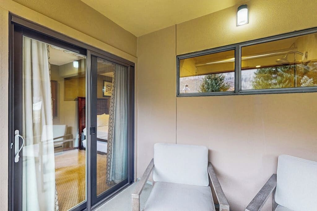 A room with a sliding glass door leading to a balcony, a small table, and a chair.