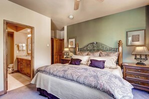 Een slaapkamer met een bed, nachtkastjes, een spiegel en een deur naar een badkamer.