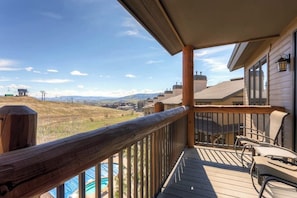 A wooden deck with a view of a mountainous landscape, a pool, and a building with a balcony. - Spacious ski-In/out condo w/free WiFi, shared pool/hot tub/gym (Steamboat Springs)