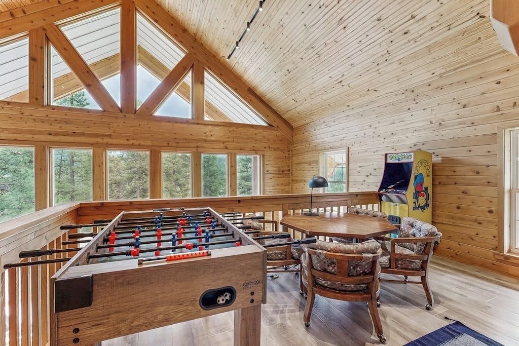 A wooden interior with a foosball table, a dining table, and chairs.