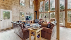Ein rustikales Blockhaus-Interieur mit Kamin, Ledersofas und großen Fenstern.