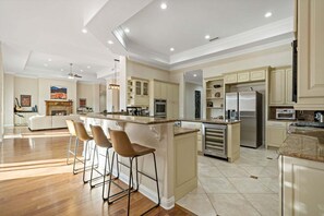 A spacious kitchen with a large island, bar stools, and modern appliances. - Rancho Agave Azul Family Retreat Near Wine Country (Murrieta)