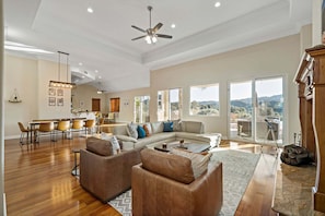 A spacious living room with a large sofa, a dining area with a long table, and a kitchen in the background. - Rancho Agave Azul Family Retreat Near Wine Country (Murrieta)
