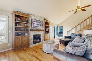 Ein Wohnzimmer mit Kamin, Holzregalen, einem runden Couchtisch, einem Ledersofa und einer Treppe.