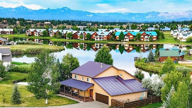 Een woonwijk met huizen, een meer en bergen op de achtergrond.