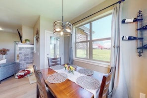 A dining area with a wooden table, woven placemats, and a hanging light fixture. - Dog-friendly house in central locale on golf course with mountain view & hot tub (Pagosa Springs)