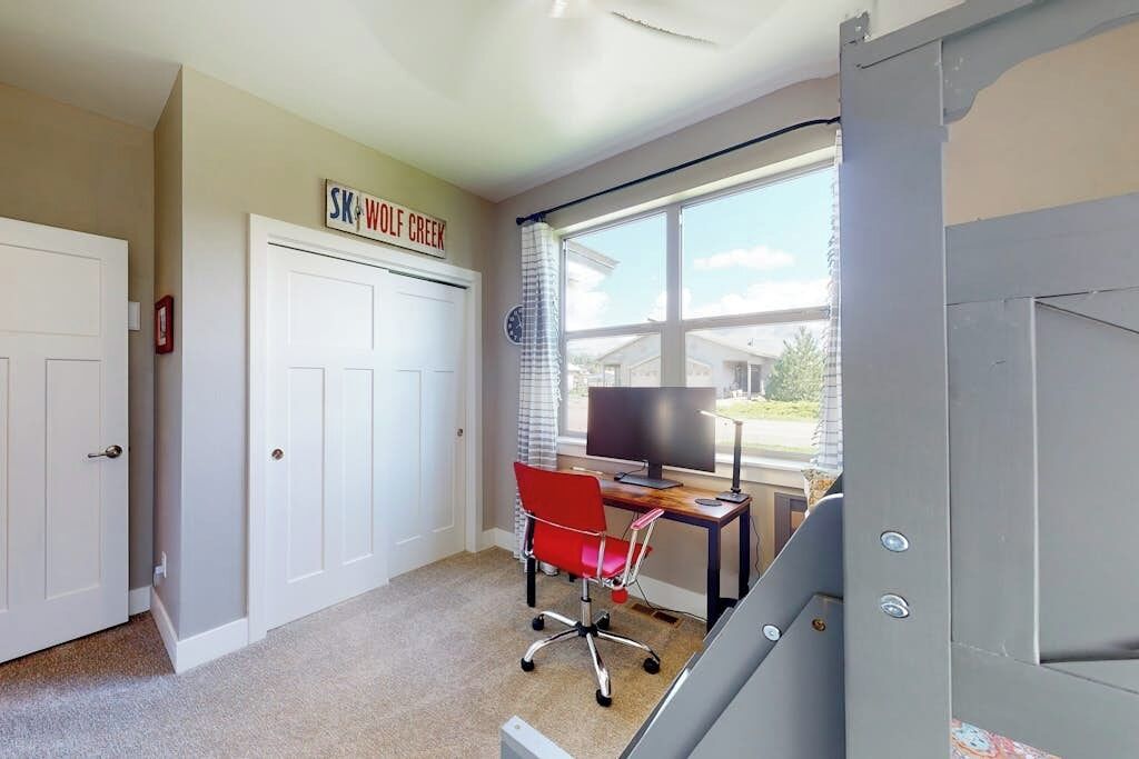 A room with a desk, chair, and a window with a view of houses.