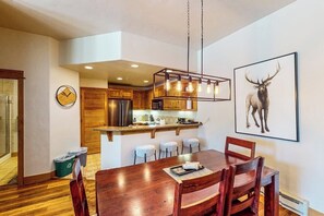 A modern kitchen with wooden cabinets, a stainless steel refrigerator, and a hanging light fixture. - Ground-floor, walk-to-lift condo w/ fireplace, W/D & shared pool/hot tubs/gym (Steamboat Springs)