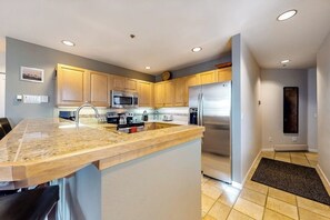 Eine moderne Küche mit Granit Arbeitsplatten, Edelstahlgeräten und hellen Holzschränken.