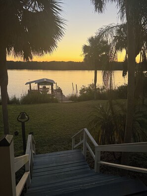 Eine Holzterrasse führt zu einem Pavillon am See bei Sonnenuntergang.