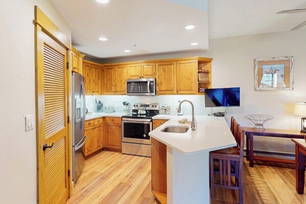 Una cocina moderna con armarios de madera, electrodomésticos de acero inoxidable y un comedor con mesa y sillas.