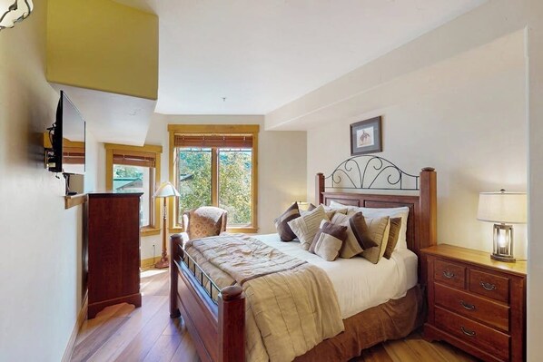 A bedroom with a bed, bedside table, lamp, and a window with blinds. - EagleRidge Lodge 206 Walk-to-gondola condo w/ fireplace, laundry & shared hot tubs/pool/gym/shuttle (Steamboat Springs)