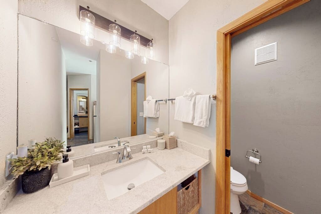 Un bagno con uno specchio grande, un lavandino e un water.