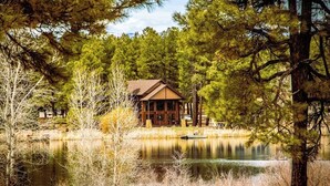 Un lodge con facciata in legno, un molo e un lago circondato da alberi.