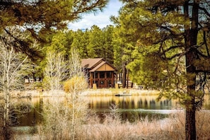 A lodge with a wooden exterior, a dock, and a lake surrounded by trees. - Lakefront home with private dock, mtn & lake views, bikes, fireplace, grill, SUP (Pagosa Springs)
