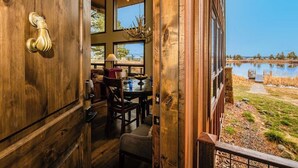 Una porta in legno con maniglia in ottone, zona pranzo con tavolo e sedie, e vista su un lago.