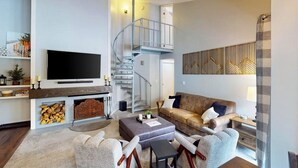 A modern living room with a fireplace, a flat-screen TV, a sofa, and a staircase. - Conveniently located condo with full kitchen, fast wifi, shared pool & hot tub (Keystone)