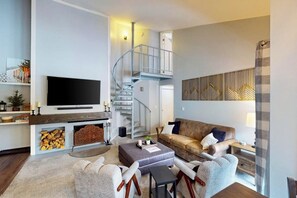 A modern living room with a fireplace, a flat-screen TV, a sofa, and a staircase. - Conveniently located condo with full kitchen, fast wifi, shared pool & hot tub (Keystone)