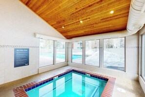 A spa area with a wooden ceiling, a pool, and windows with a view of the outside. - Conveniently located condo with full kitchen, fast wifi, shared pool & hot tub (Keystone)