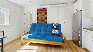 Een kamer met een bank, een eettafel, een keukenhoek en een raam.