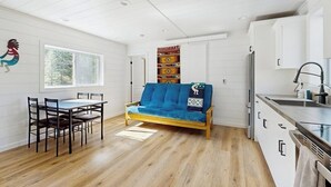 Een moderne keuken met witte kasten, een eethoek met een houten tafel en stoelen, en een blauwe bank.