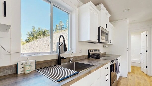 Een moderne keuken met een inbouwfornuis, een magnetron en een raam met uitzicht op een woestijnlandschap.