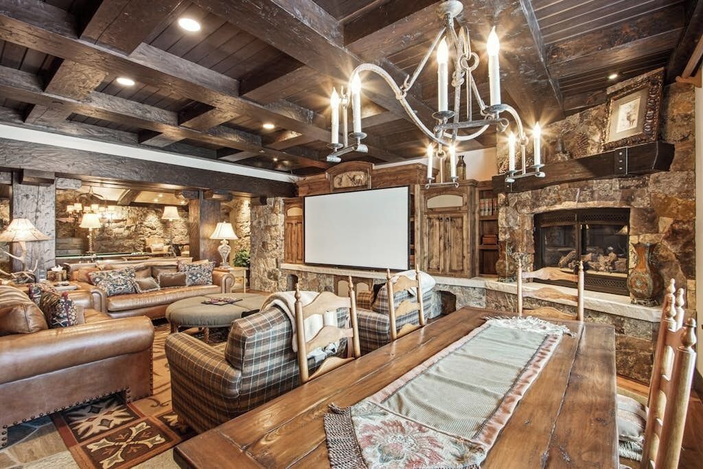 A rustic interior with a fireplace, wooden beams, and a large screen.
