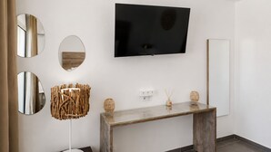 A modern room with a mounted TV, a glass-top console table, and three wall-mounted mirrors.