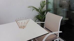 A white table with a beige chair, a decorative metal object on the table, and a sign with text on the wall.