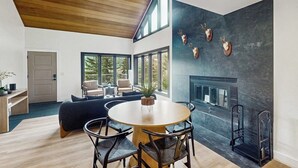 Ein modernes Interieur mit Essbereich, Kamin und großem Fenster.