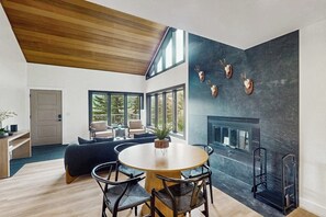 Ein modernes Interieur mit Essbereich, Kamin und großem Fenster.